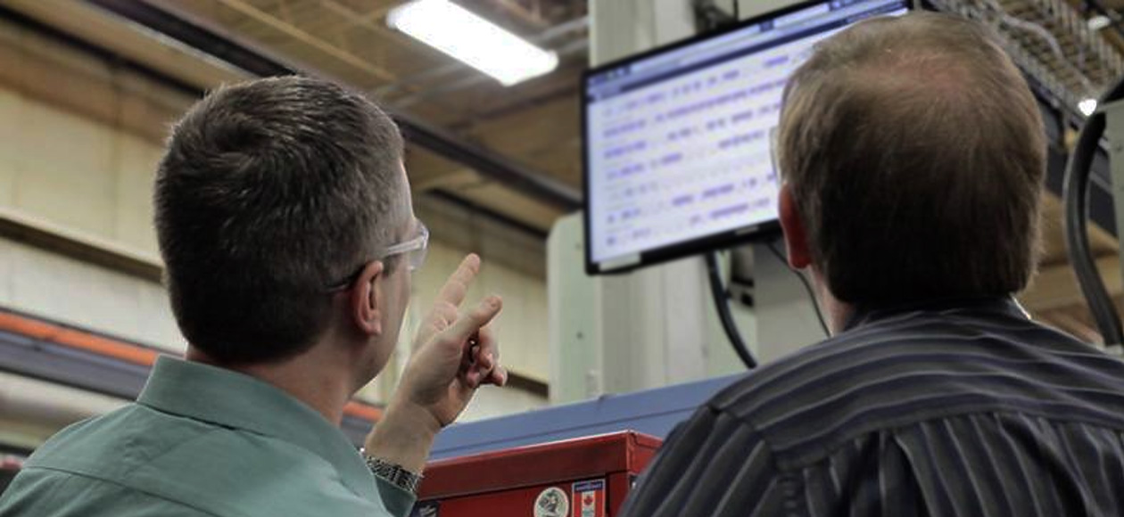 men looking and pointing at monitor with Shiftworx data displayed in factory freepoint technologies