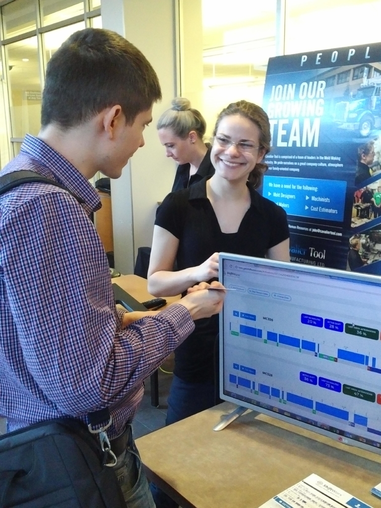 woman smiling at man in front of monitor displaying shiftworx software at freepoint technologies booth
